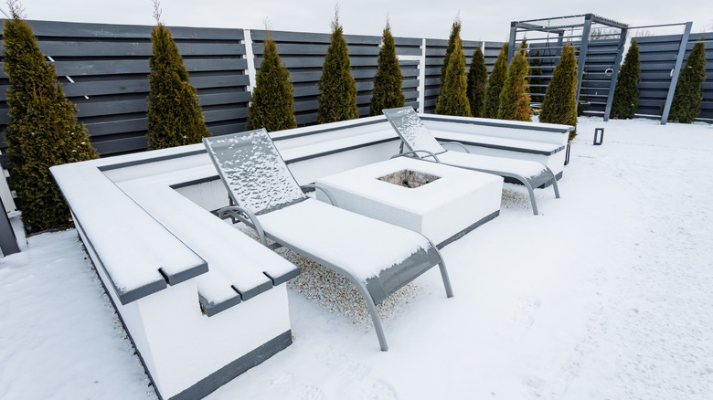 A concrete patio and deck chairs are covered in snow