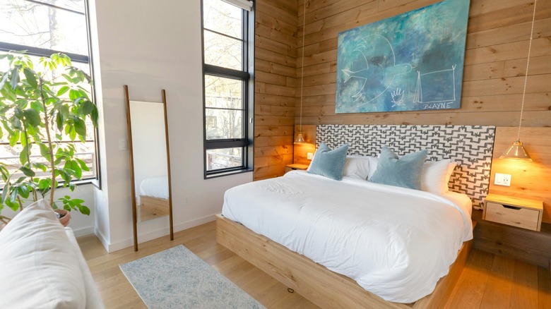A bright bedroom with a wood feature wall and large artwork above the bed.