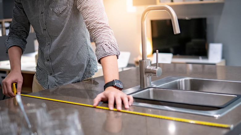 Someone measuring counter space with tape measure