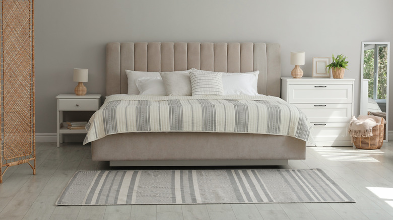 Bed with a rug at the foot of the bed on wooden flooring