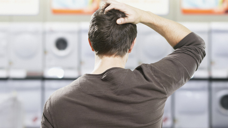 Man scratching head near appliances