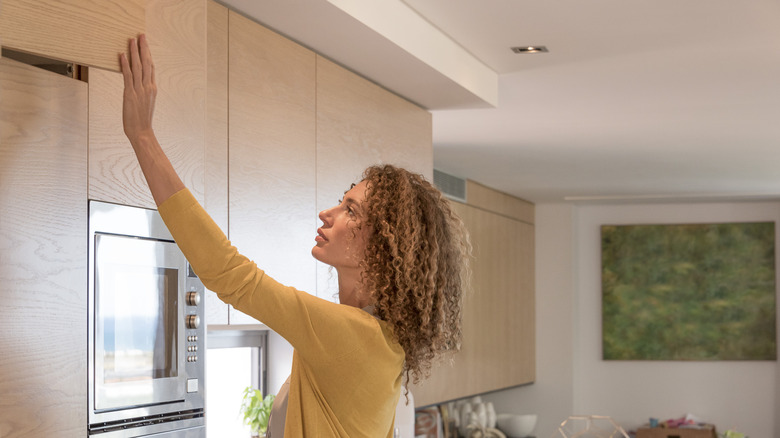 A woman closing a vinyl wrapped cabinet in her kitchen.