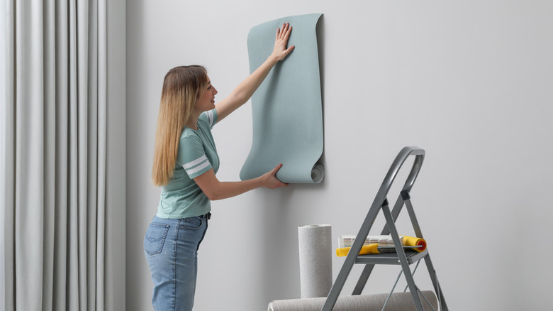 Woman putting up wallpaper