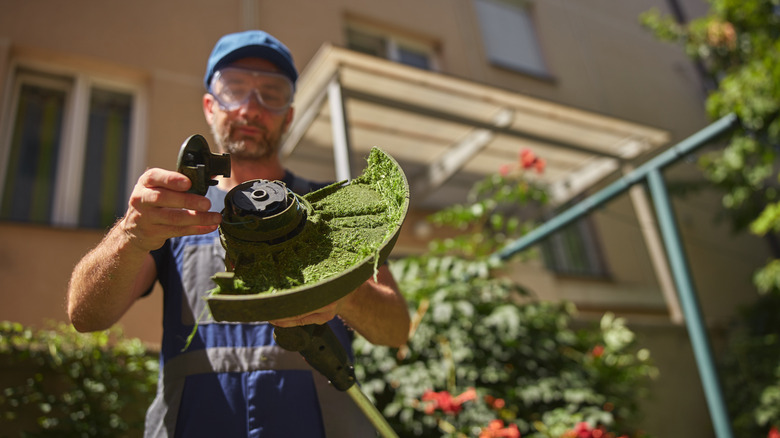 A middle-aged man with a beard changes the string out from a weed trimmer.