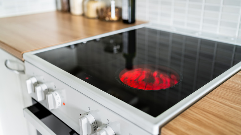 A black glass stovetop in use with one burner glowing red