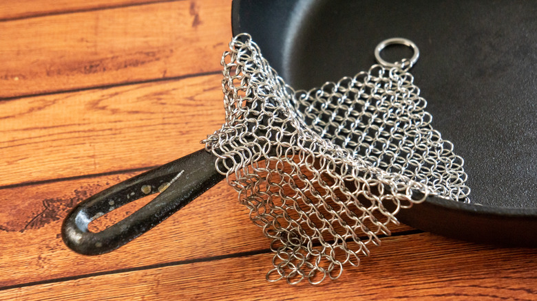 A chainmail scrubber resting on a cast iron skillet