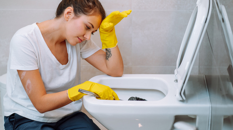 A young woman cleaning a toilet
