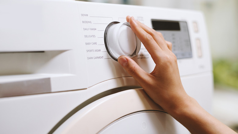 Woman selecting the delicates setting on washing machine.
