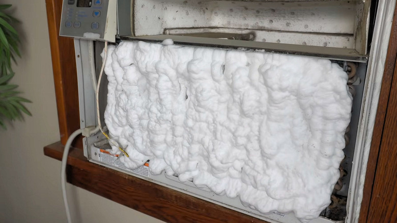 The inside of a window air conditioner unit covered with cleaning coil foam.