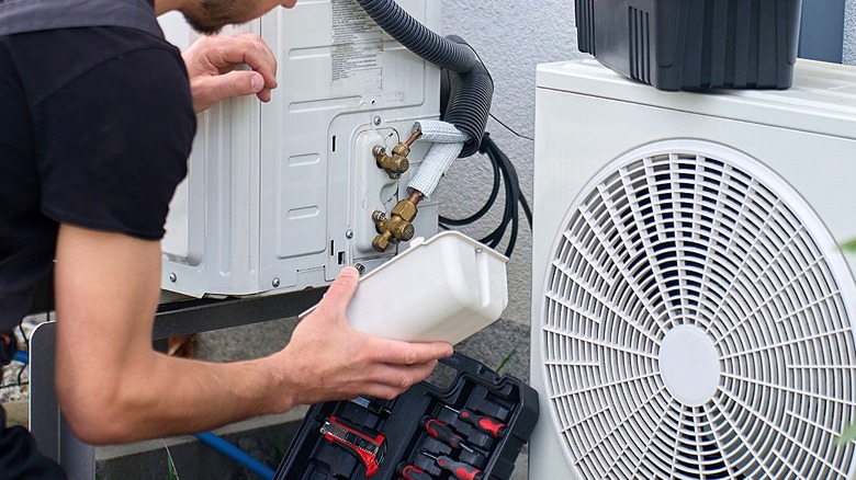 An HVAC professional removes cover from an AC unit for maintenance