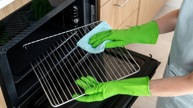 Person with gloves cleaning oven and oven rack