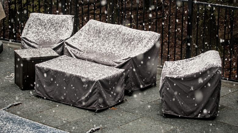 patio with covered furniture as snow falls