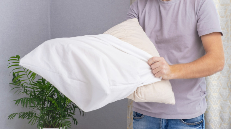 Man tucking a freshly cleaned pillow inside of a clean white pillowcase.