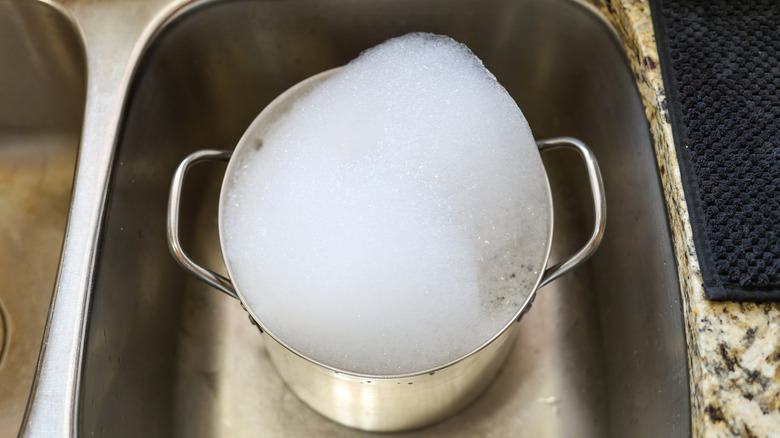 Pot full of soapy water soaking in sink.