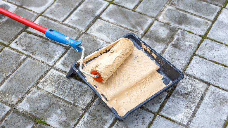 Paint roller in tray of paint on ground