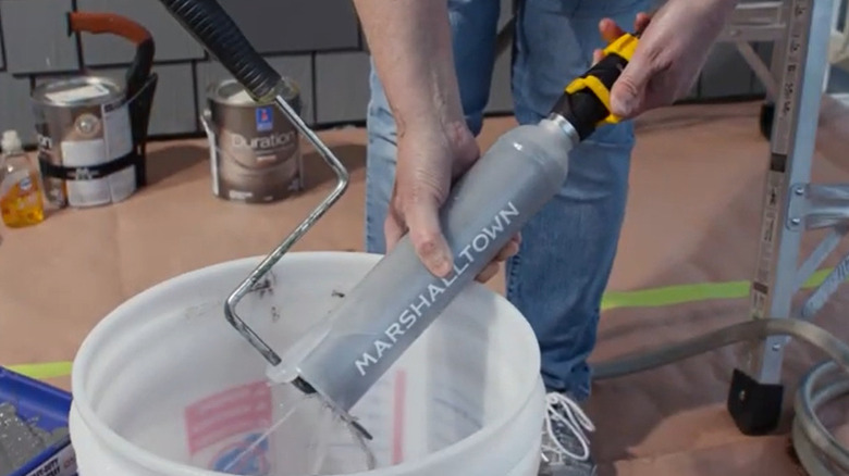 Paint roller cover cleaner being used to clean a paint roller