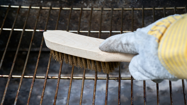 Person scrubs down their grill grates with a brush