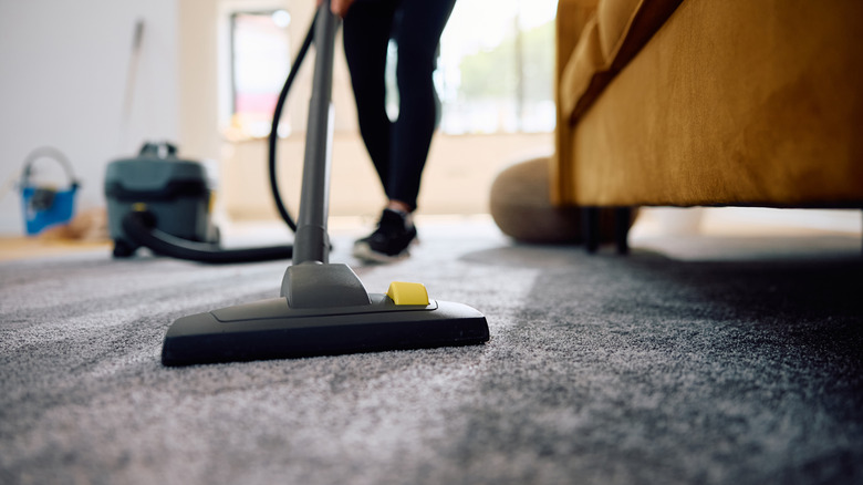 A person cleaning a rug with a vacuum cleaner