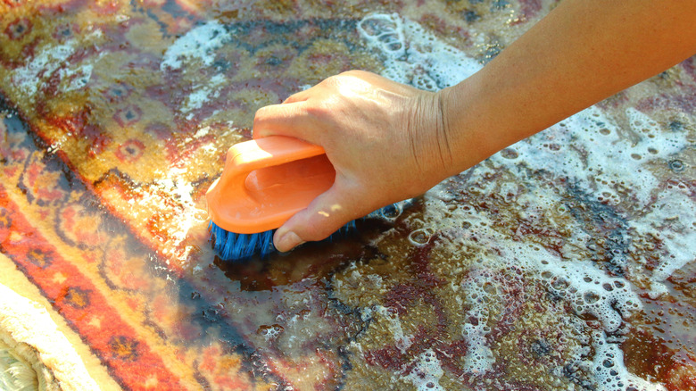 Close-up of a person cleaning with lots of shampoo and water.