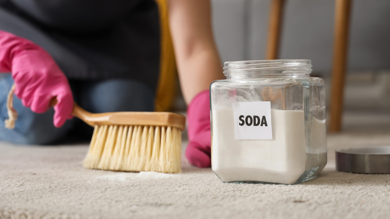 Close-up of a person cleaning a carpet with baking soda.