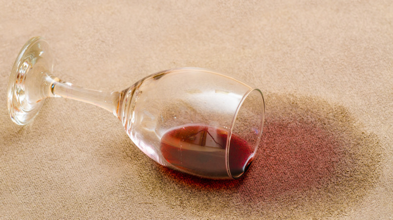 A spilled glass of red wine on a carpet
