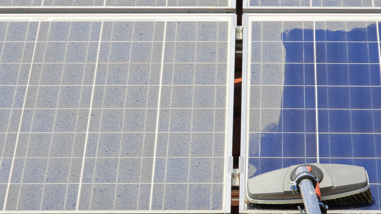 A broom cleaning dirty solar panels
