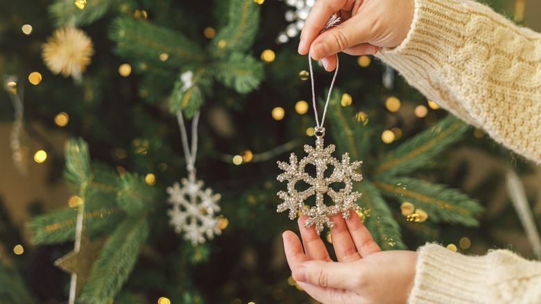 Hands holding a vintage glass snowflake shaped ornament