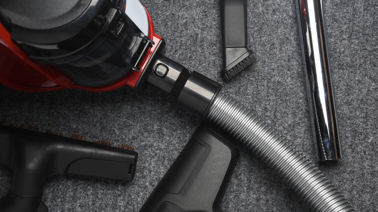 A vacuum cleaner and assorted attachments on a floor