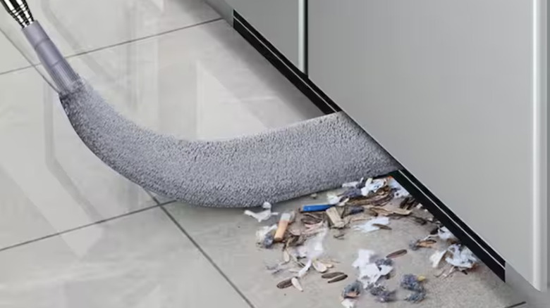 A retractable gap dust cleaner tool removes debris from under a refrigerator