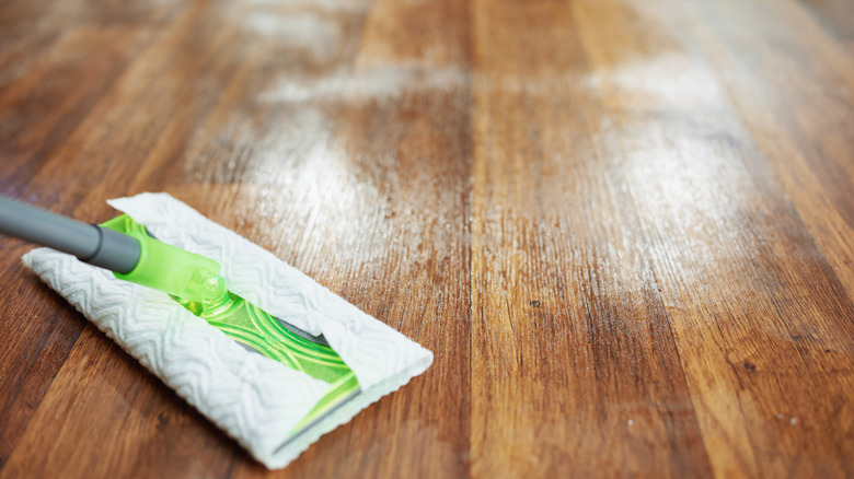 A Swiffer dry mop cleans a vinyl wood plank floor