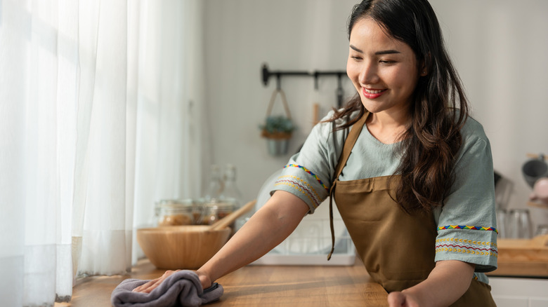 Woman smiling and cleaning the kitchen