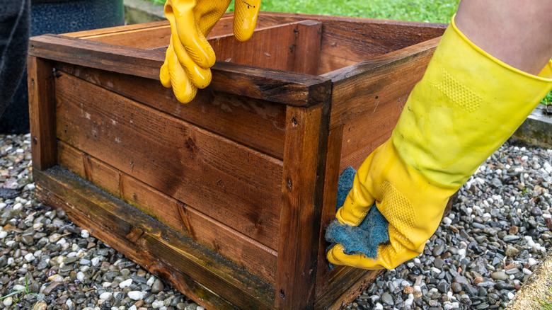 Gloved hands scrubbing wooden box