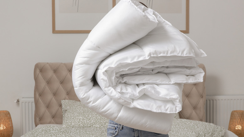 A person carrying a folded comforter