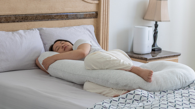 A woman sleeping with a pregnancy pillow