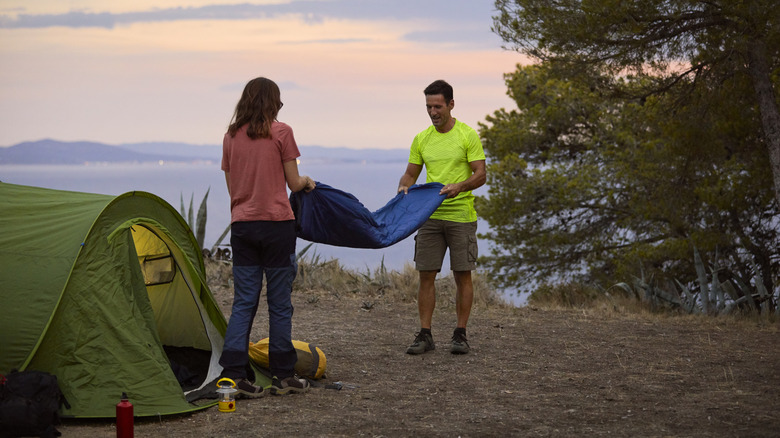 Two people folding a sleeping bag after camping