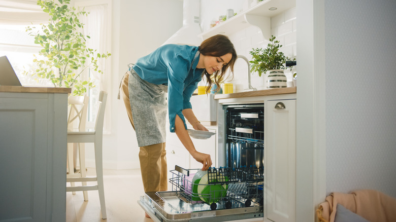 woman loading plates into dishwasher