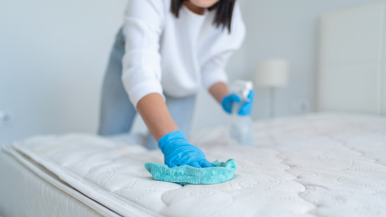 person with spray bottle wiping down clean mattress