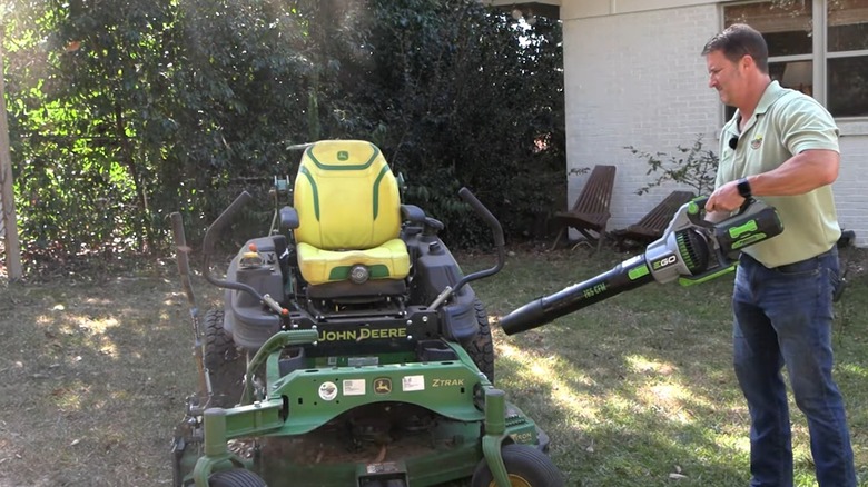 Man cleaning a mower deck with a leaf blower