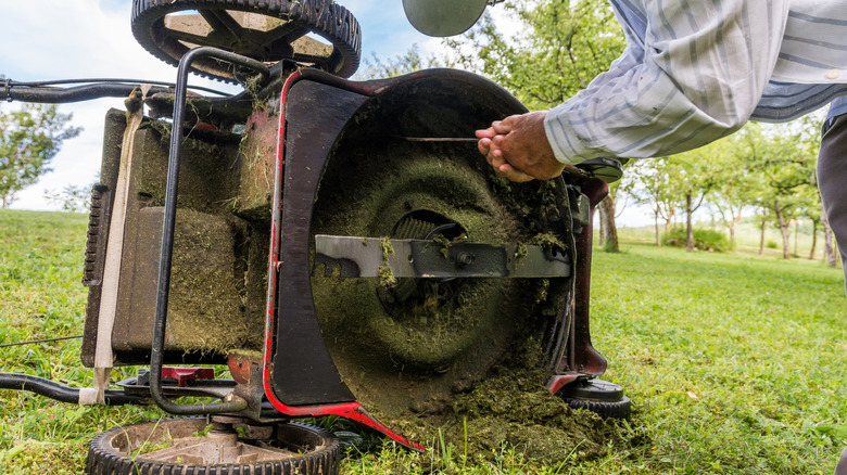 Man cleans underside of mower