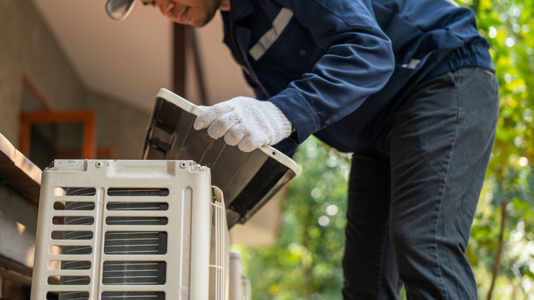 An air conditioning technician placing cover on outdoor ac unit