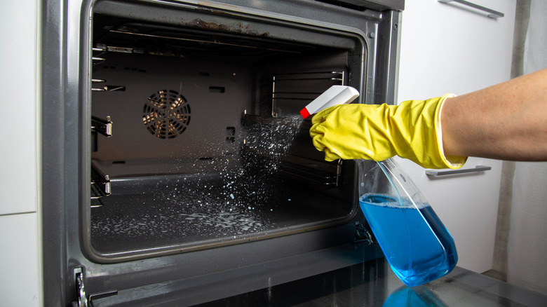 Spraying oven with a cleaning solution