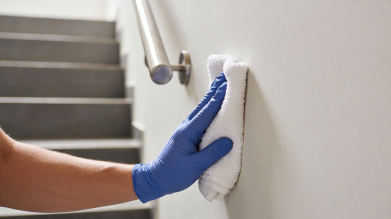 Gloved hand wiping wall