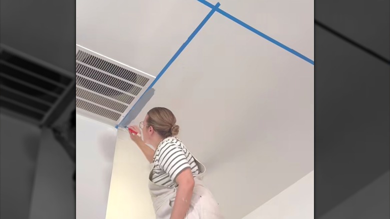 Person painting ceiling with painters tape square