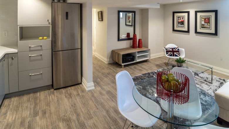 Basement apartment with kitchenette, dining table with chairs, and small living area.