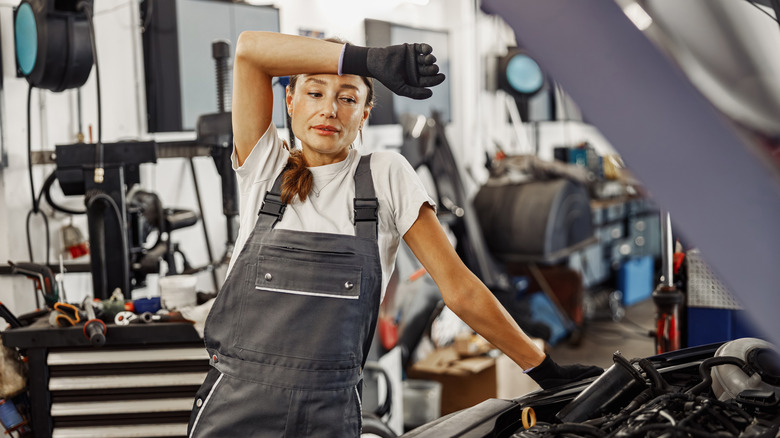 Woman in garage wiping sweat off of her face with her arm