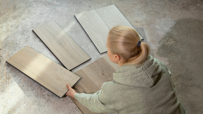 A woman looks at vinyl flooring samples laid out on carpet.