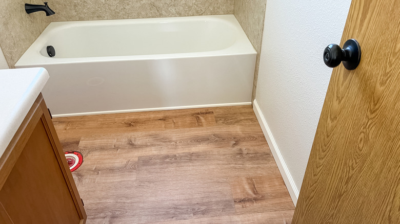 A bathroom with newly installed luxury vinyl planks that mimic hardwood floors.