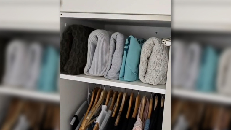 Folded sweaters on closet shelf