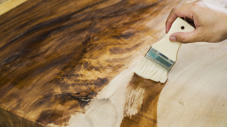 person applying stain to a wood veneer piece