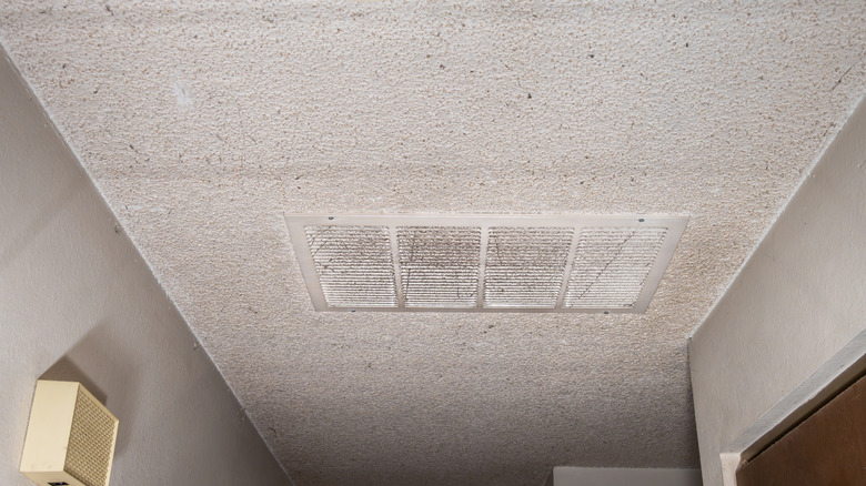 A hallway with a popcorn ceiling and a large air vent